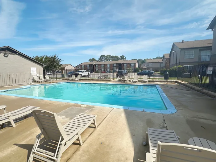 Inviting residential swimming pool area with lounge chairs and clear blue skies, perfect for relaxation.
