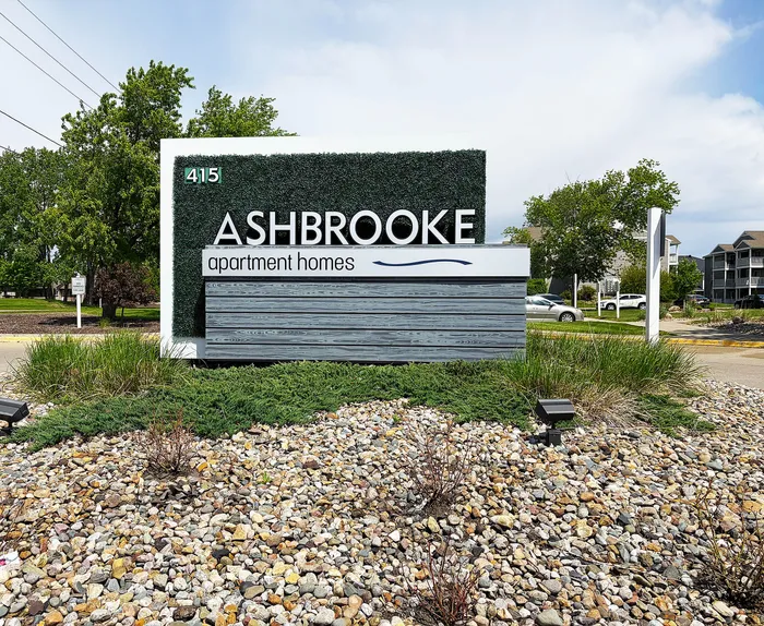 Contemporary Ashbrooke apartment homes entrance sign surrounded by lush greenery and modern landscaping.