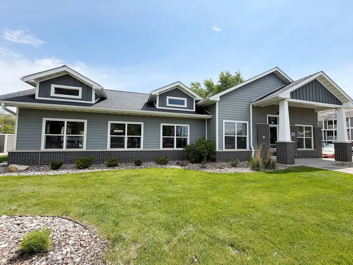 Charming single-story home with a modern gray exterior, featuring large windows and a welcoming front porch, surrounded by well-maintained greenery and landscaping.