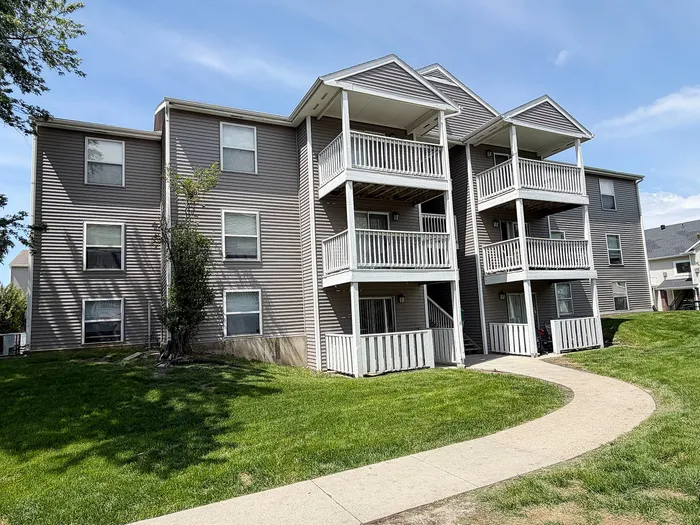 Charming apartment building with multiple balconies and lush green surroundings, perfect for modern living.