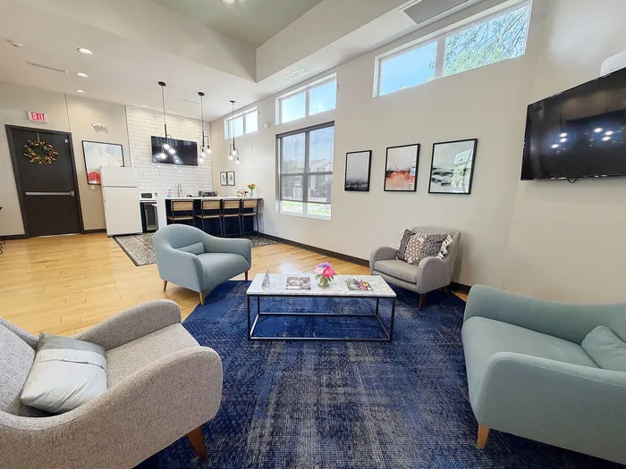 Inviting living space with modern decor, featuring cozy armchairs, a stylish coffee table, and a sleek kitchen area with bar seating.