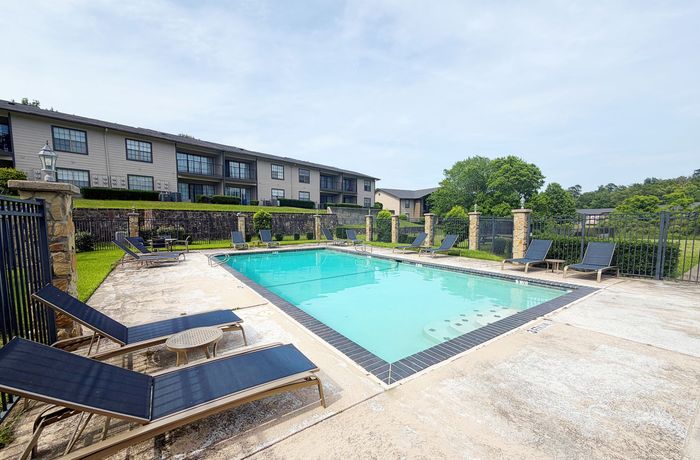 Inviting outdoor pool area with comfortable lounge chairs and lush greenery, perfect for relaxation and enjoyment.