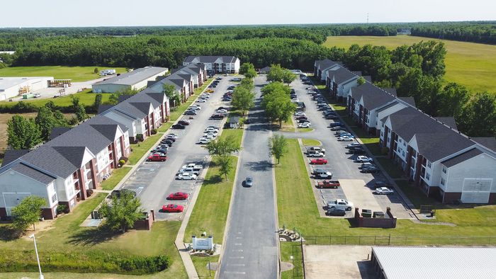 Serene aerial view of charming apartment complexes, surrounded by lush greenery and ample parking space.