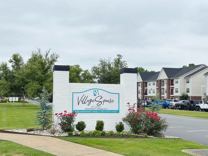 Charming exterior view of Village Square of Cabot Apartment Community with neatly manicured landscaping and modern buildings.