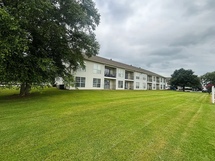 Charming apartment complex with spacious lawns and lush trees, perfect for serene living.