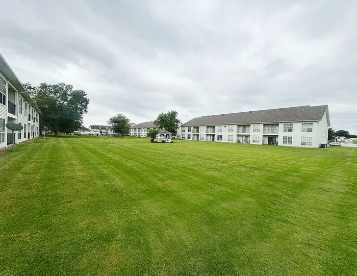 Expansive green lawn in front of modern apartment buildings, offering serene outdoor spaces and beautiful landscaping.