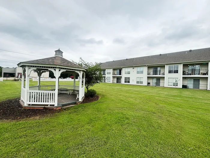 Charming apartment complex with a scenic gazebo set on lush green lawns, perfect for relaxation and community gatherings.