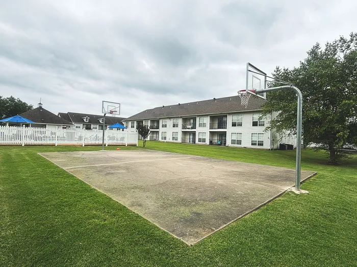 Inviting apartment complex with a well-maintained basketball court and spacious green lawn, perfect for outdoor activities.