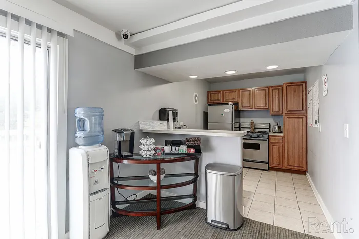 Modern kitchen with warm wooden cabinets, stainless steel appliances, and a cozy breakfast bar overlooking a bright living area with large windows.