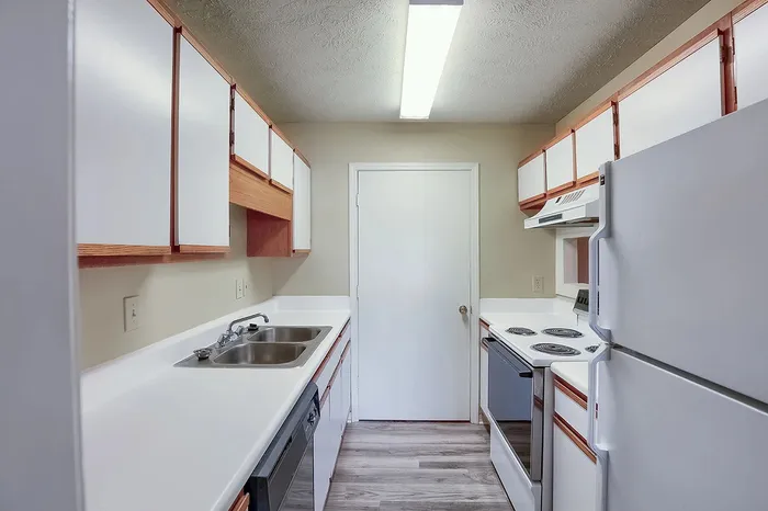 Bright and inviting kitchen with sleek white cabinetry, modern appliances, and wood-patterned flooring.