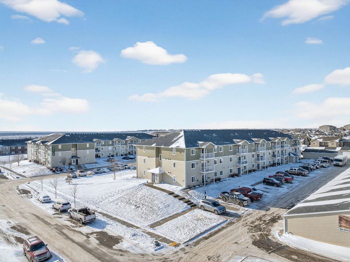Charming apartment complex in a serene winter landscape, offering modern living with ample parking and spacious balconies.