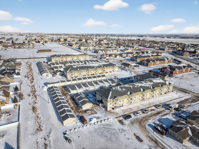 Charming aerial view of a snow-covered residential community showcasing modern townhouses and elegant apartment buildings under a bright blue sky.