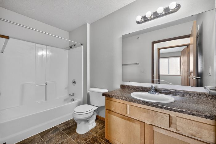 Bright and modern bathroom featuring a sleek countertop, elegant vanity mirror, and a full-size bathtub with shower.