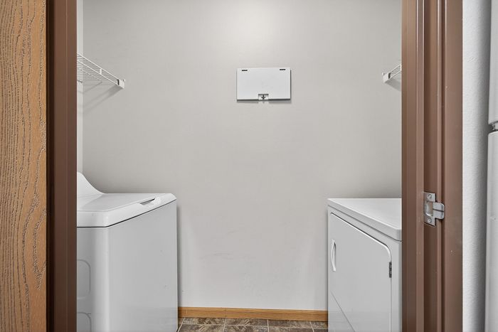 Modern apartment laundry room with sleek washer and dryer set, framed by a stylish wooden door.