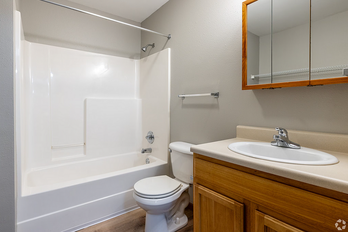 Modern bathroom featuring a sleek vanity, large mirror, and pristine bathtub-shower combination.