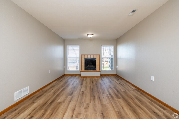 Inviting living room with elegant wood flooring, large windows for ample light, and a cozy built-in fireplace.
