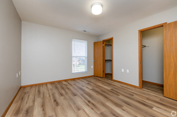 Bright and inviting bedroom with elegant wooden flooring, ample closet space, and a large window for natural light.