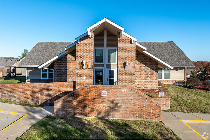 Charming brick apartment complex with welcoming entrance, lush green surroundings, and modern architectural design.