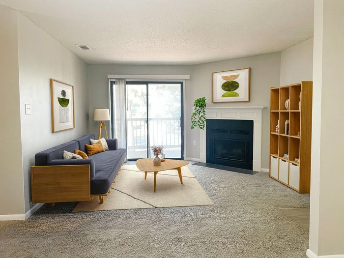 Bright and cozy living room with a stylish wooden sofa, modern decor, and inviting fireplace, complemented by a large window offering natural light.