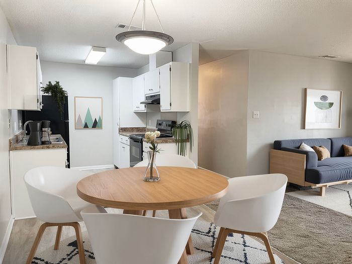Modern open-concept kitchen and living area with sleek white cabinetry, stylish dining set, and cozy seating.