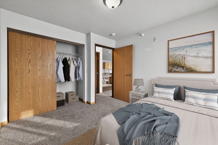 Cozy bedroom with plush carpeting, spacious closet, and elegant decor, featuring a serene beach painting.