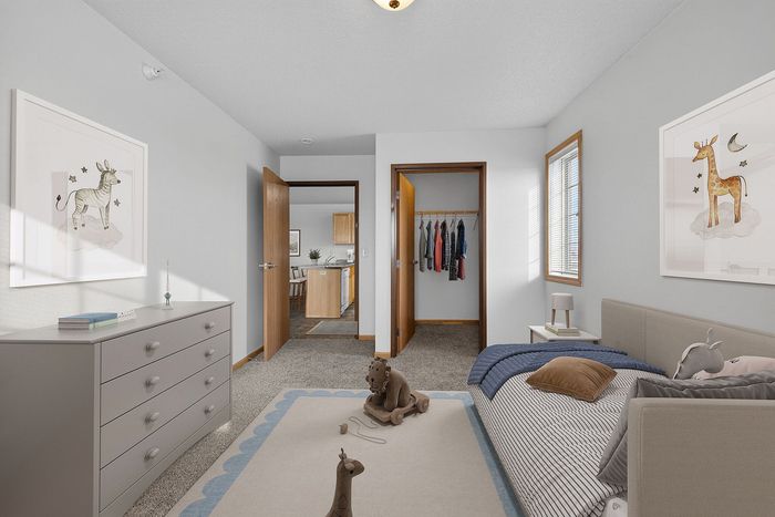 Cozy bedroom with playful decor, featuring a spacious closet and natural light streaming in through the window.