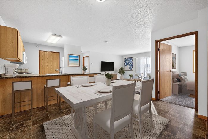 Bright open-concept dining and living area with modern kitchen and cozy bedroom entry.