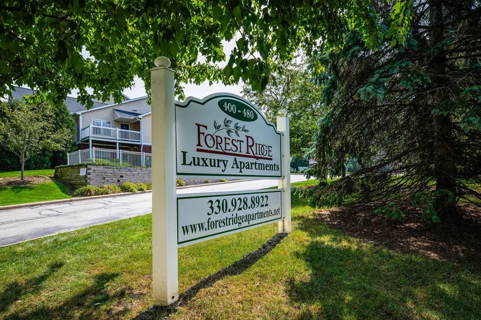 Inviting sign for Forest Ridge Luxury Apartments surrounded by lush greenery, showcasing serene and upscale living.