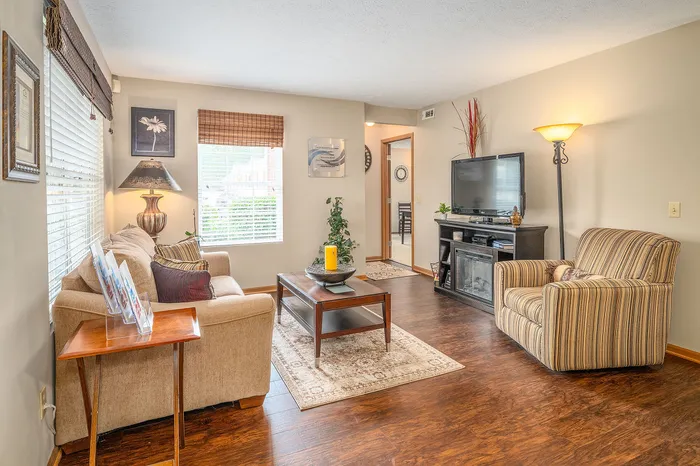 Inviting living room with warm hardwood floors, cozy beige sofa, and elegant decor highlighted by natural light.