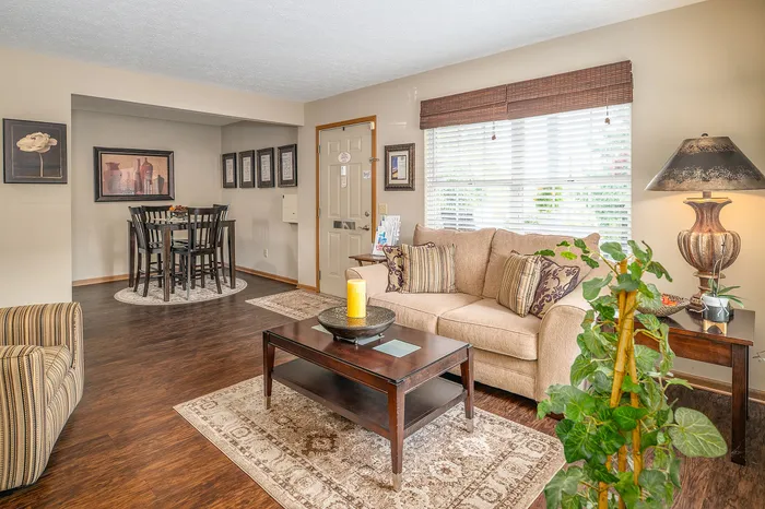 Elegant living room featuring a cozy beige sofa, chic coffee table, artful decor, and inviting natural light from large windows.