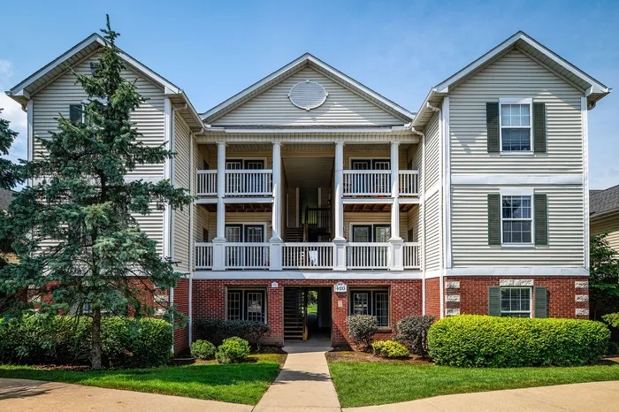 Charming apartment building with elegant balconies, lush greenery, and a welcoming entrance.