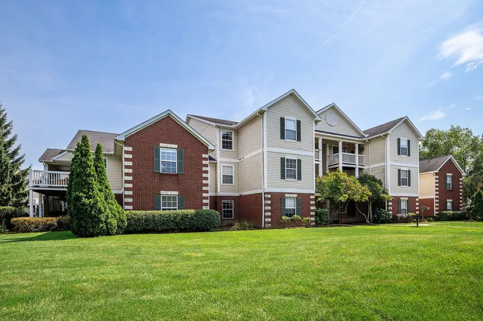 Charming multi-story apartment building with modern brick facade, lush green lawn, and serene surroundings.