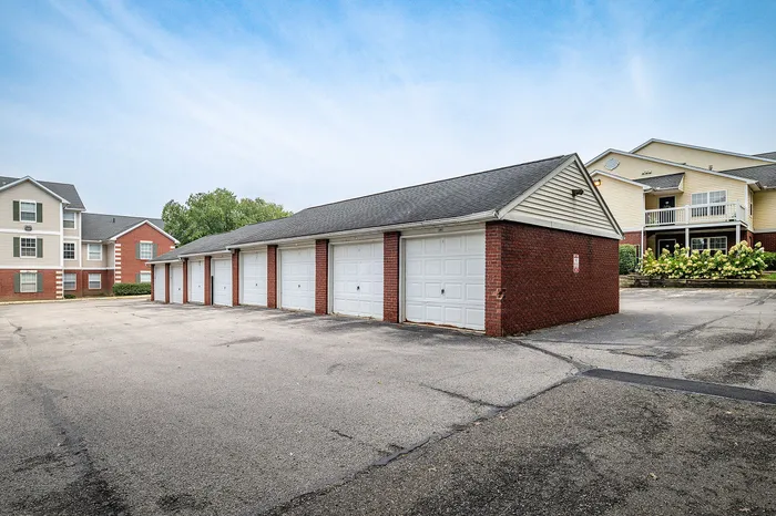 Charming apartment complex with brick facade and convenient row of private garages in a quiet, well-maintained community.