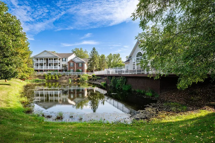 Charming apartment building with a picturesque pond and lush greenery, offering a serene and inviting living environment.