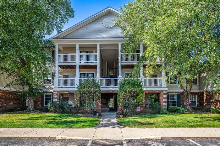Charming apartment complex exterior with classic white railings, lush greenery, and inviting balconies.