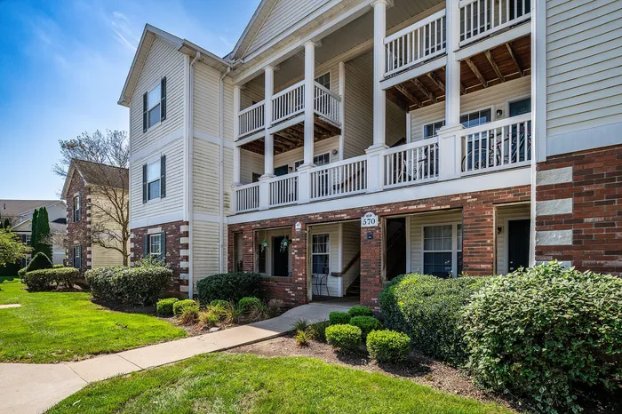 Charming apartment complex with classic brick and siding exterior, featuring spacious balconies and lush landscaping.