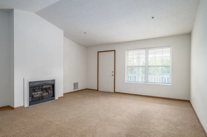 Inviting living room with elegant fireplace, plush carpet, and ample natural light from large windows.
