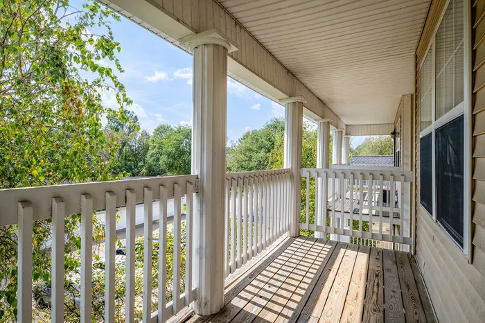 Charming apartment balcony with elegant white columns offering serene views of lush greenery.