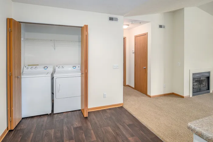 Contemporary apartment with in-unit washer and dryer, rich wooden floors, cozy carpeted space, and a stylish fireplace.