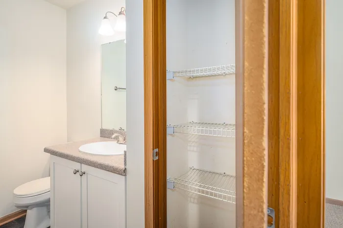 Bright and modern bathroom featuring a sleek vanity with ample countertop space and an adjacent built-in shelving unit ideal for organized storage.