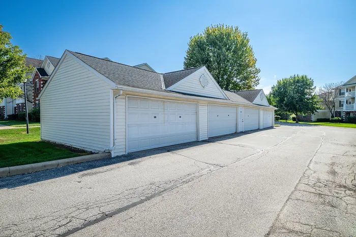 Charming street view of detached garages in a vibrant neighborhood, surrounded by lush greenery under a clear blue sky.