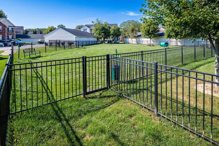 Beautiful community park area with lush green lawn, fenced enclosures, and charming neighborhood views.