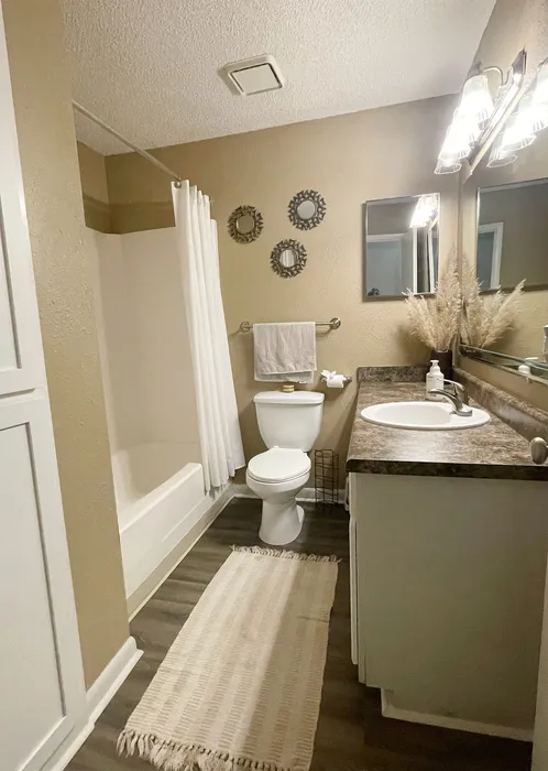 Elegant bathroom featuring a modern vanity, sleek countertops, and cozy shower with stylish decor accents.