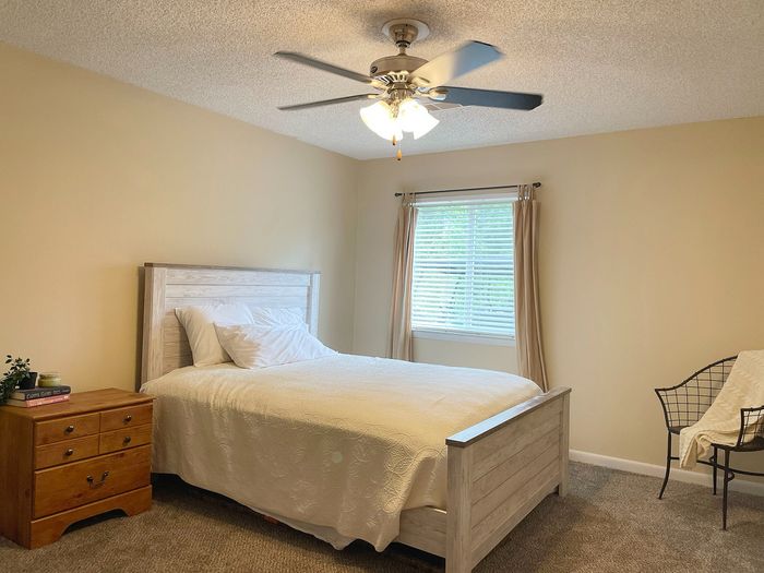 Inviting bedroom featuring a cozy bed with plush pillows, a wooden nightstand, and a window offering natural light.