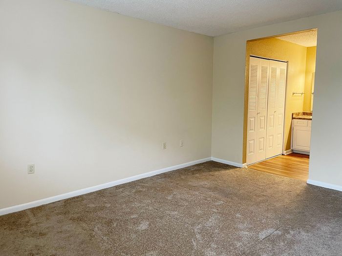 Inviting living space with plush carpet leading to a cozy nook and bright adjoining area.