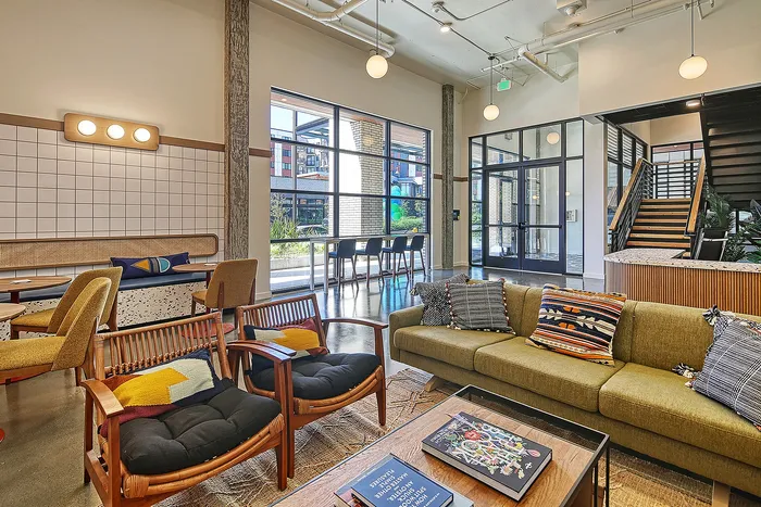 Modern, inviting living space with stylish seating areas, vibrant cushions, and abundant natural light through large windows.