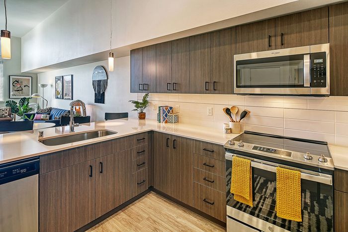 Modern kitchen with sleek cabinetry and integrated appliances, opening to a stylish living area with contemporary decor and vibrant art pieces.