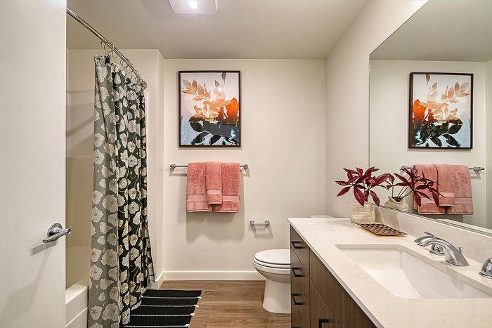 Contemporary bathroom featuring elegant floral shower curtain, chic artwork, and vibrant decor enhancing a serene atmosphere.