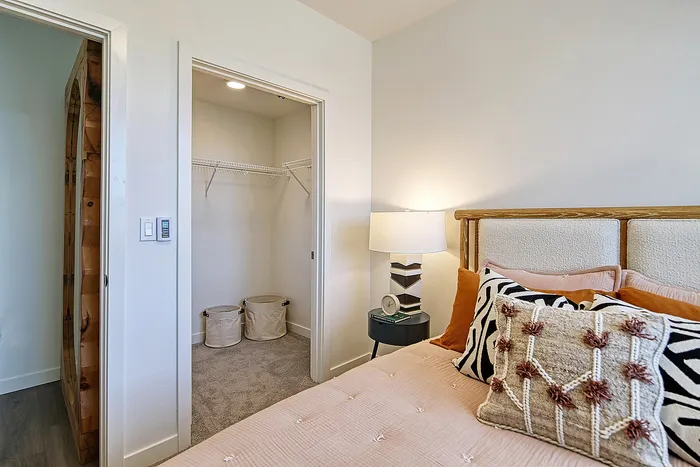 Cozy bedroom with elegant decor, featuring a plush bed, designer pillows, soft lighting, and a spacious walk-in closet.