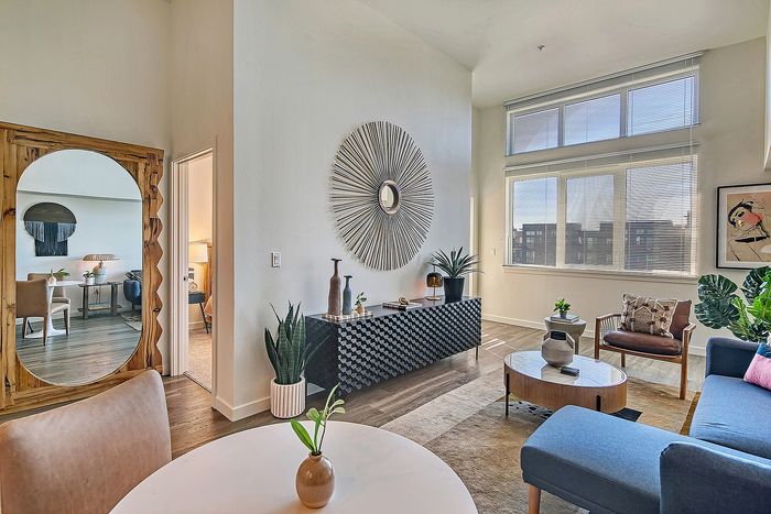 Chic and modern living room with large sunlit windows, stylish decor, and elegant seating area, perfect for relaxation.